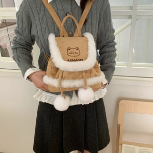 Detail of cute cat embroidery and white faux fur pom-poms on a camel bucket backpack