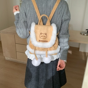 Detail of cute khaki bucket backpack with white faux fur trim and plush pom-poms charms