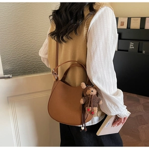 Brown leather hobo bucket bag with a cute bear charm shown in a lifestyle setting