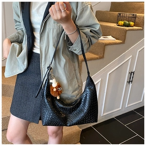 Close-up of black woven texture shoulder bag with a brown plush animal charm