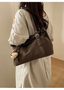 Détail du sac cabas rétro marron foncé avec bandoulière réglable et accessoire d'ours