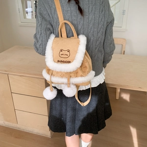 Detail of khaki corduroy backpack with white faux fur trim and plush pom-poms on the flap