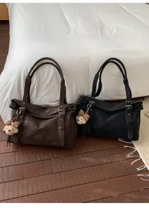Détail de grands sacs fourre-tout noir et marron foncé avec breloques d'ours et lanières cuir