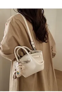 Detailansicht der weißen Leder-Beuteltasche mit Metallschloss und Plüschlamm-Anhänger