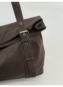 Détail du sac en cuir marron foncé avec boucle argentée réglable et œillets métalliques