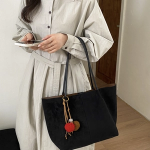 Détail du grand sac cabas noir mat avec pompon bicolore porté par un mannequin