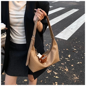Close-up of brown woven leather tote bag with a cute monster plush charm detail