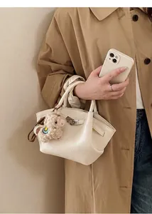 Detail der weißen Beuteltasche aus Leder mit süßem Plüschschaf-Anhänger und Metallverschluss