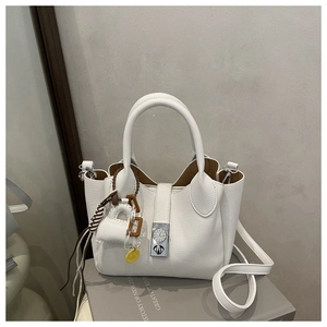 Detalle del bolso tote de cuero blanco con hebilla de cierre en forma de reloj de plata
