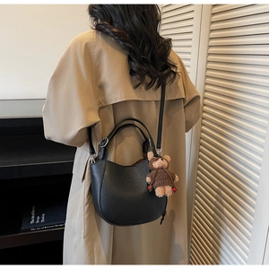 Detail of black lychee grain bucket bag with teddy bear charm and adjustable strap