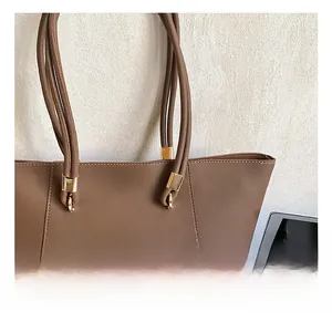 Close-up of golden metal rings and leather strap details on a brown tote bag