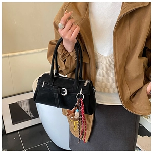 Detail of black suede handbag featuring silver ring buckle and star charm keychain