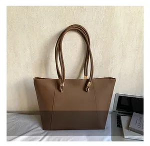 Detailed view of the dark brown tote bag featuring vertical stitching and golden hardware