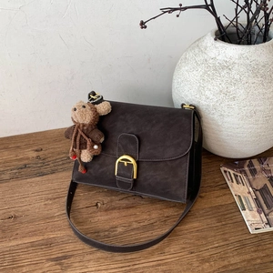 Detalle de bolso bandolera vintage mate con hebilla de herradura dorada y colgante de ratón