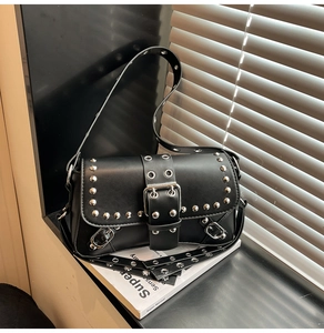 Macro view of black punk shoulder bag with silver rivets and metal buckle detail