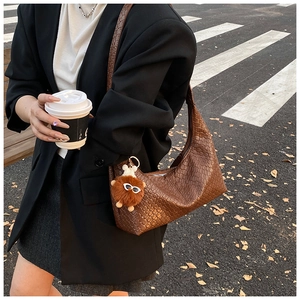 Detail of woven brown hobo bag with plush monster charm and street style aesthetic