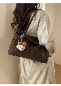 Détail d'un sac à bandoulière rétro marron foncé avec un ours en peluche et sangle