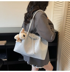 Détail d'un sac cabas bleu en similicuir avec un pendentif chien en peluche et boucle