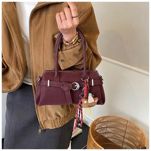 Detail of dark red vintage baguette bag with cute bear charm and metal buckle accent
