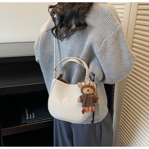 White pebbled leather bucket bag with cute bear charm shown in a minimalist interior