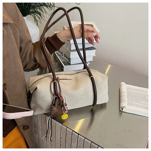 Detailed close-up of retro cream shoulder bag with brown straps and cute pendant charms