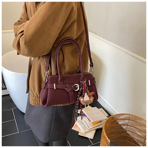 Detail view of burgundy vintage matte handbag with side scarf and plush charm decor