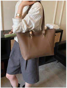 Detail of brown tote bag with retro gold hardware and contrast stitching for commute