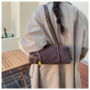 Detail of dark brown vintage suede bowling bag with a mini charm on the shoulder strap