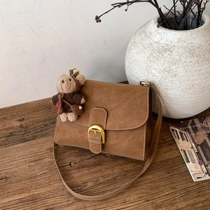 Detalle de bolso bandolera vintage en ante marrón con elegante hebilla dorada