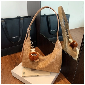 Detail of camel brown woven leather tote bag featuring a cute plush bear charm accessory