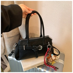 Detail of black suede Boston bag featuring silver buckle and cute plush animal charm