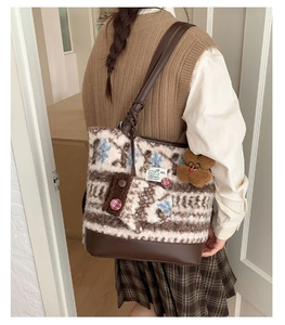 Detail of knit fair isle tote bag with leather base and cute bear charm pendant