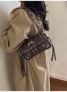 Close-up of vintage brown leather underarm bag with silver rivets and metal buckle detail