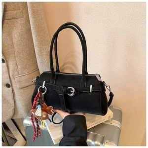 Detail of matte black Boston bag with silver buckle and plush bear charm accent