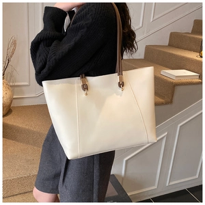 Detail view of cream tote bag with contrast brown straps and gold metal hardware