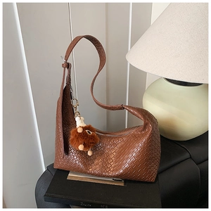 Detail of brown woven hobo bag with textured finish and cute plush charm accessory
