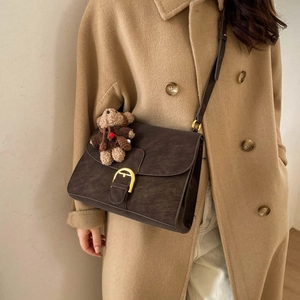 Bolso bandolera vintage marrón oscuro con hebilla dorada y colgante de oso en modelo