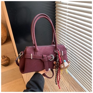 Detail of burgundy matte boston bag with bear charm and adjustable shoulder strap
