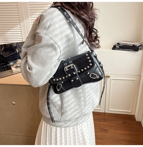 Detail of black punk shoulder bag featuring silver rivets and large metal buckle detail