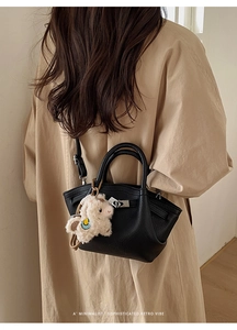 Seitenansicht der schwarzen Eimer-Tasche aus Leder mit Alpaka-Anhänger am Modell