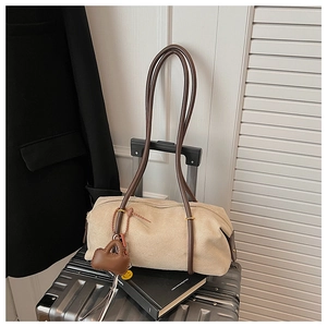 Detail of beige cylinder suede shoulder bag with brown leather handles and small charm
