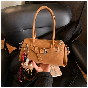 Detail of vintage matte brown top handle bag with metal buckle and plush bear charm