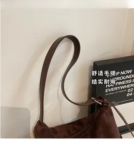 Detail of dark brown suede tote bag featuring slim leather straps and matte texture