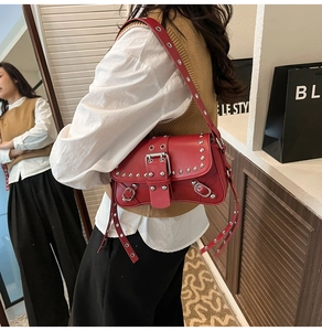 Red punk style shoulder bag with silver eyelets and rivets shown in a stylish fashion setting