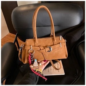 Close-up of a brown leather Boston bag on a chair with a cute bear charm and metal buckle