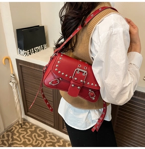 Detail of red leather shoulder bag featuring silver rivets and large metal buckle