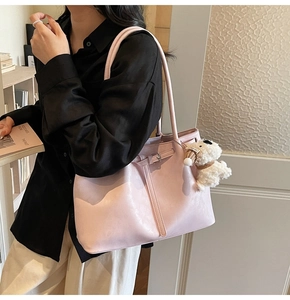 Détail du cabas en cuir rose avec boucle décorative et breloque chiot en peluche