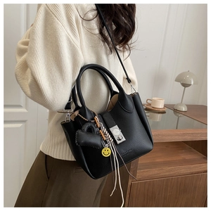 Detalle de bolso en cuero granulado negro con cierre metálico y colgante de corazón decorativo