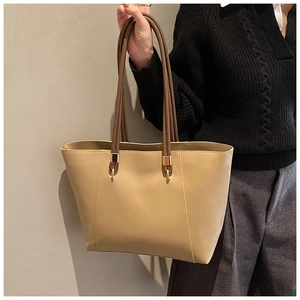 Detail of the large tote bag with apricot faux leather and brown handles with gold buckles