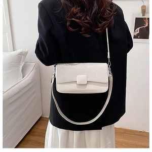 Modern white square crossbody bag worn by a model in a minimalist home setting